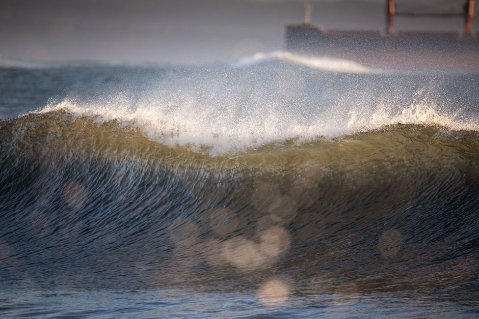 Dramatic ocean wave at Ocean Shores, Washington with a ship in the background.
