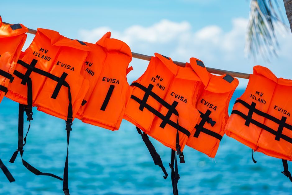 Close-up of orange life jackets labeled 'MV ISLAND EVISA' against a vibrant ocean background.